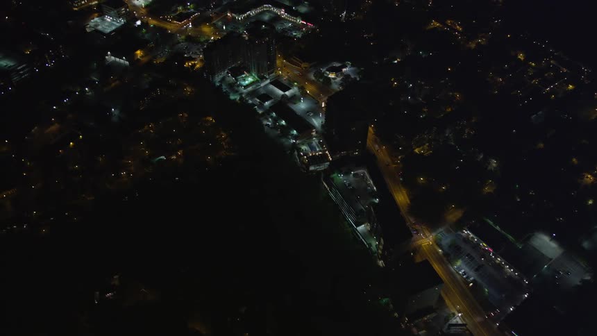 Aerial view of Buckhead Georgia at night as the camera follows a road through the city