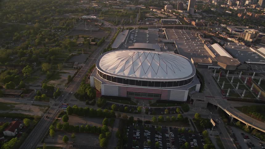 A stunning aerial orbit of Georgia Dome capturing the iconic sports arena and Atlanta skyline during a hazy and gorgeous sunset