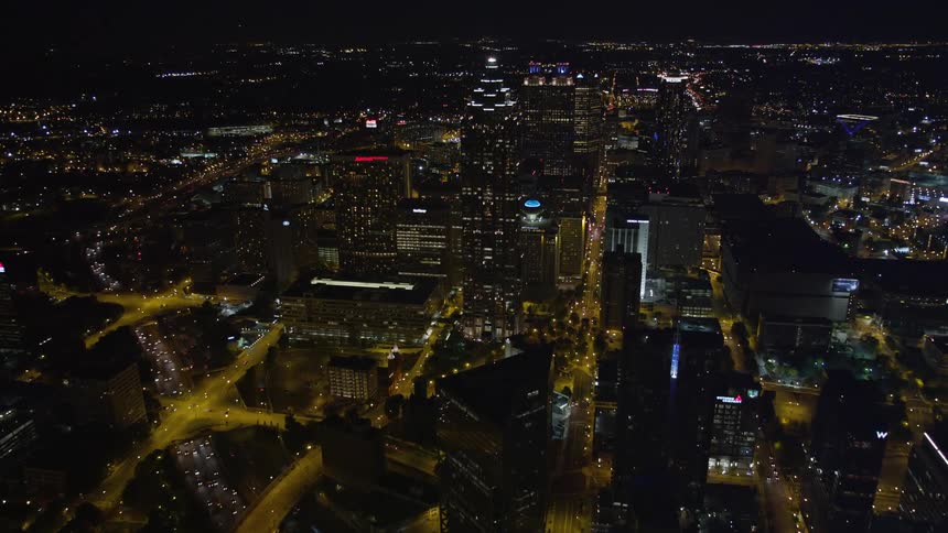A stunning aerial view of Downtown and Midtown Atlanta at night flying past Bank of America Plaza towards the metropolis