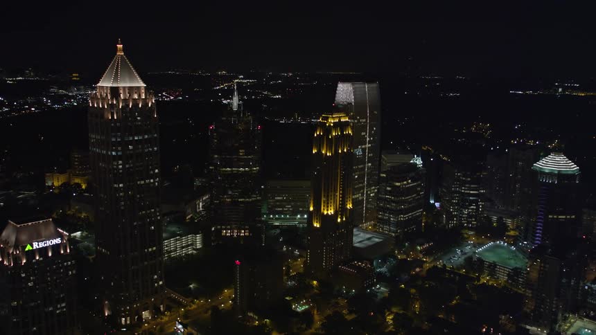 An aerial video footage showcases an impressive architectural building One Atlantic Center standing tall amidst a bustling metropolitan city and towering skyscrapers at nighttime in Midtown Atlanta Georgia