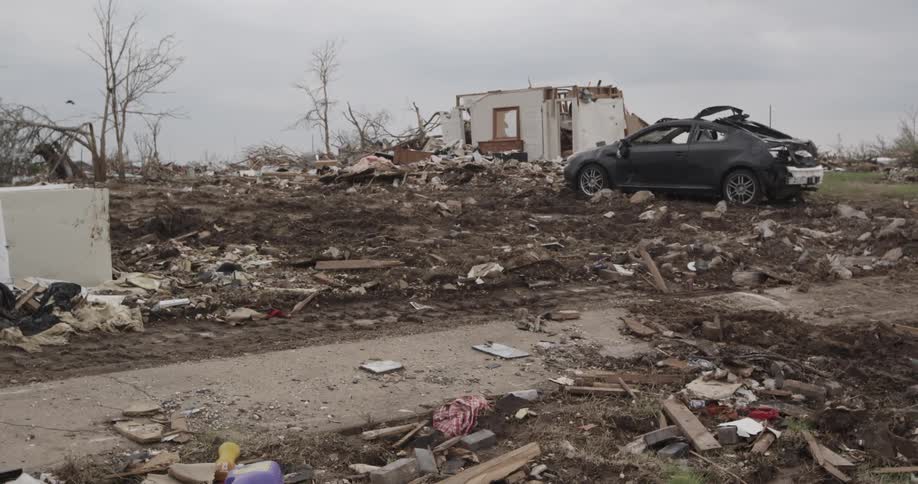 A mangled car sitting near storm debris