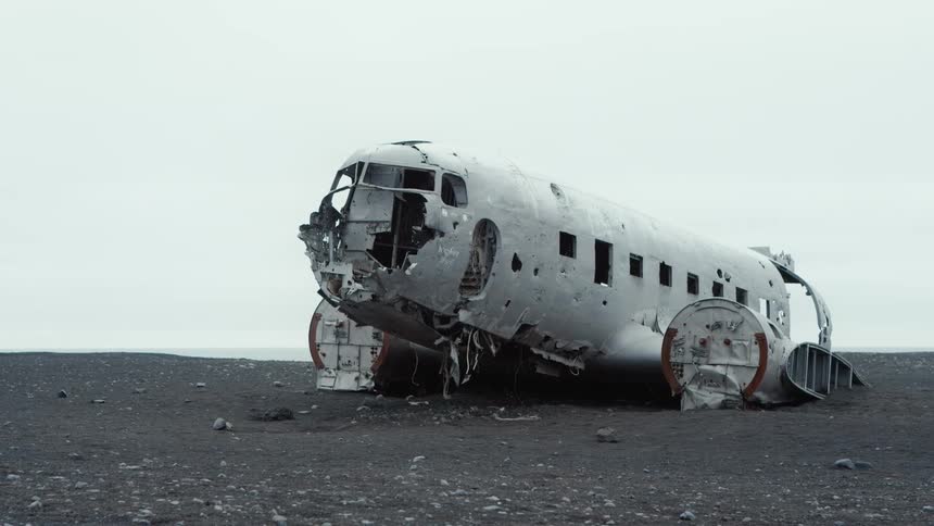 Old plane wreck sits partially buried in dirt on plain