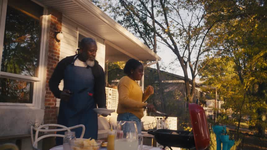 A girl serves a man food from the grill