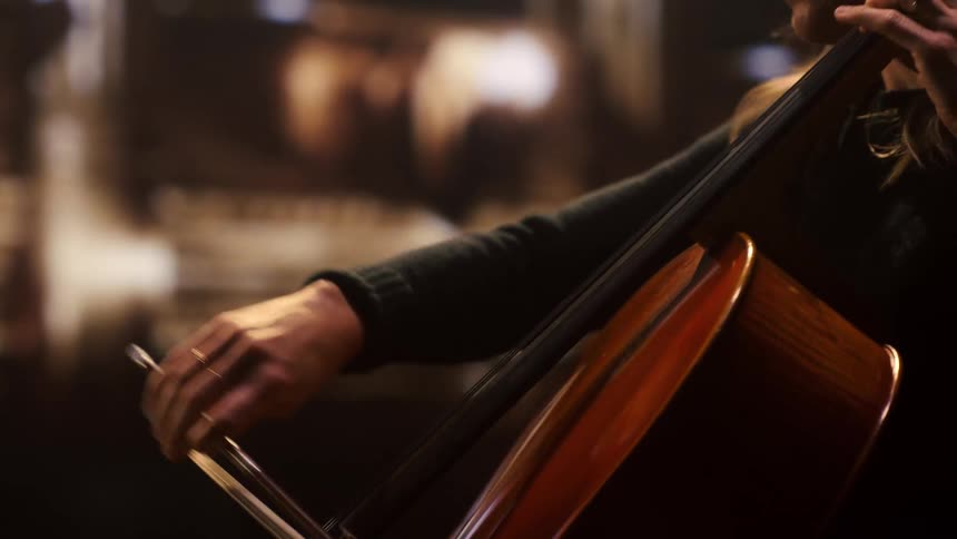 A woman is sitting and playing the cello