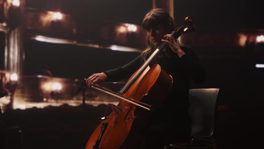 A female musician playing a cello on a stage