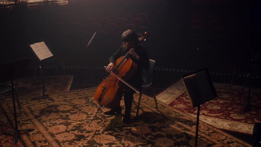 A woman is sitting down and playing the violin