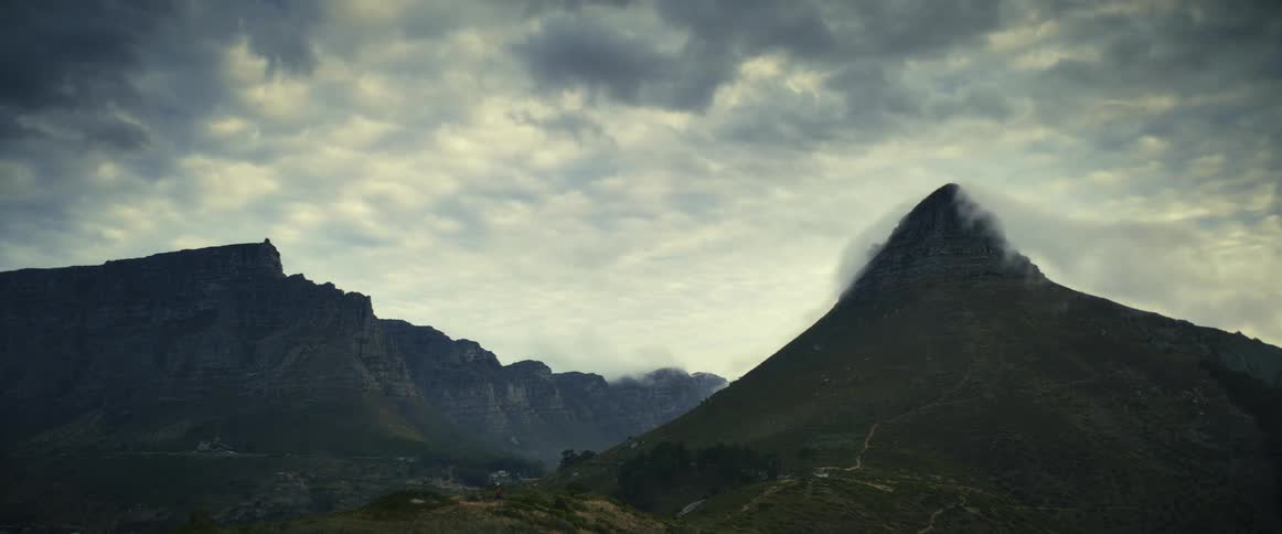 Clouds move over a mountain range as fog moves around a mountain peak