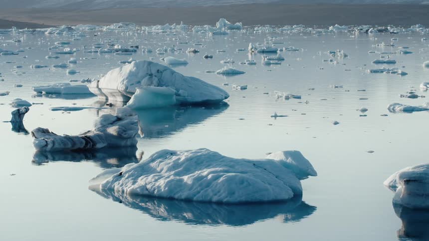 Icebergs scattered in calm water with a mountain on the horizon