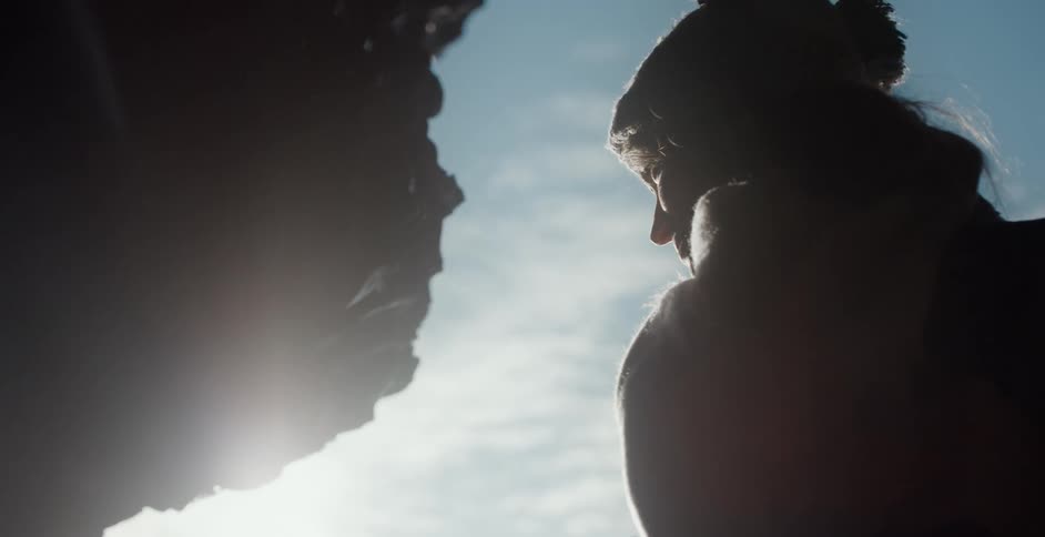 A silhouetted woman in a winter coat and hat outside on a sunny day