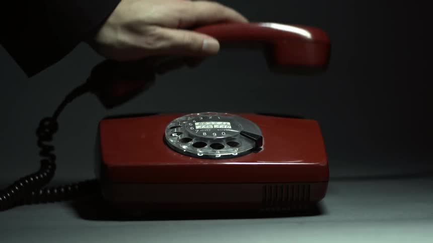 Person picking up the receiver on an old-style rotary dial phone