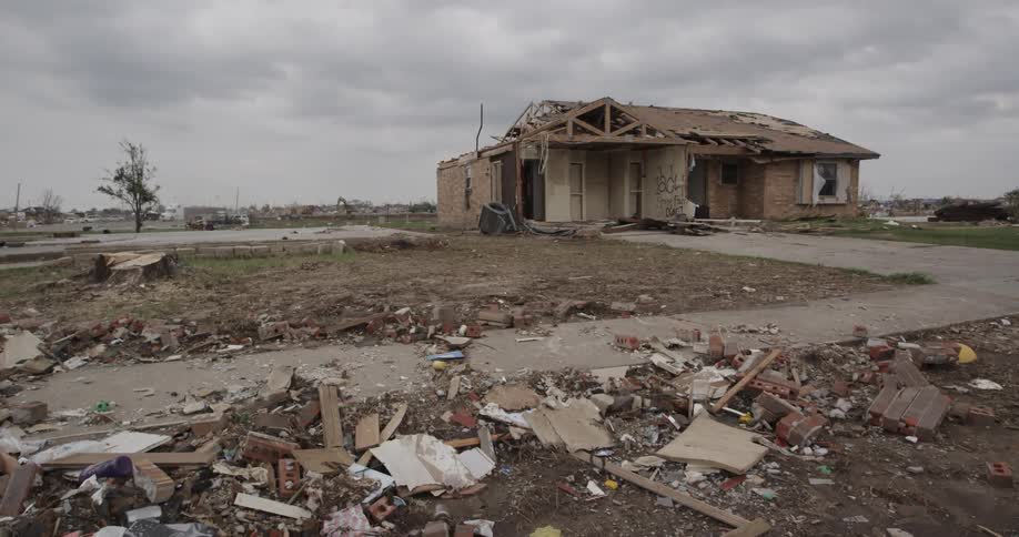 A semi truck slowly travelling through a residential area that was devastated by a storm
