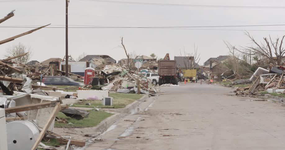 Traffic passing through a devastated area as crews clean up storm debris