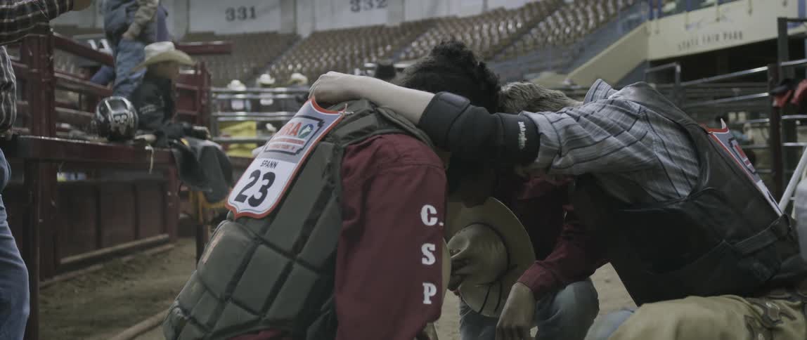A group of rodeo cowboys kneeling in prayer