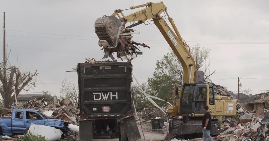 An excavator clears rubble after a storm