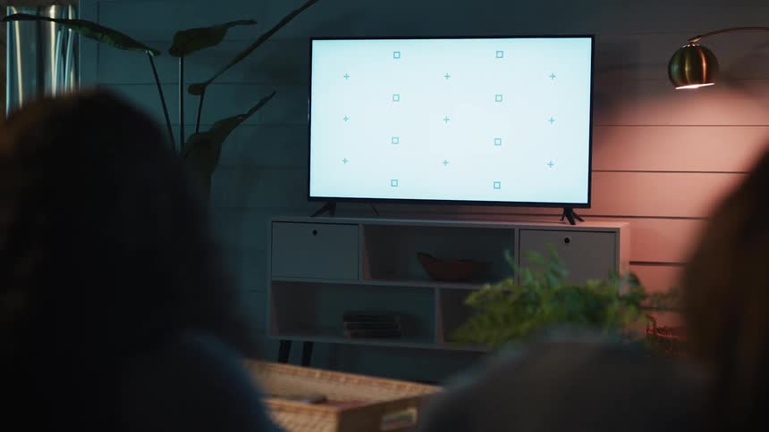 A person using their smartphone while watching television in a living room