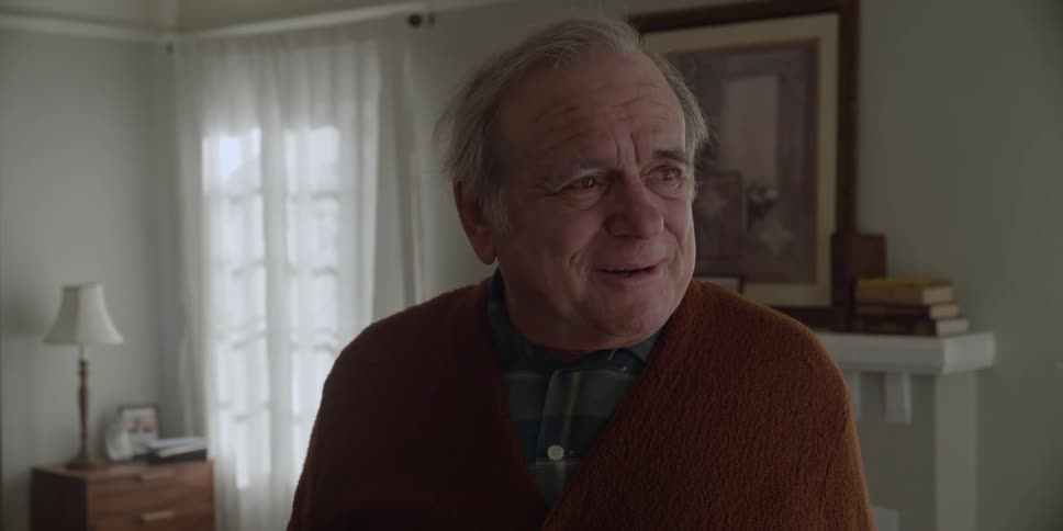 A man turns around and smiles while standing in his living room