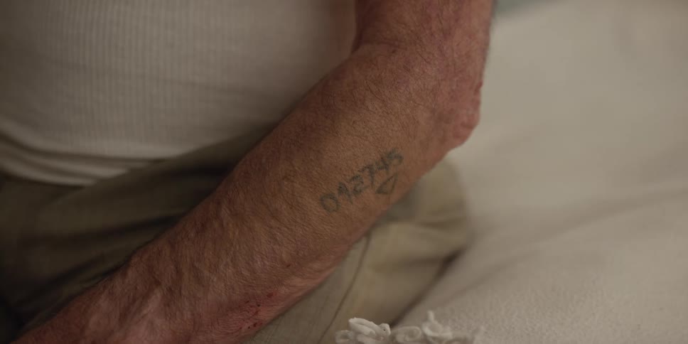 An elderly man with a tattoo of numbers on his arm