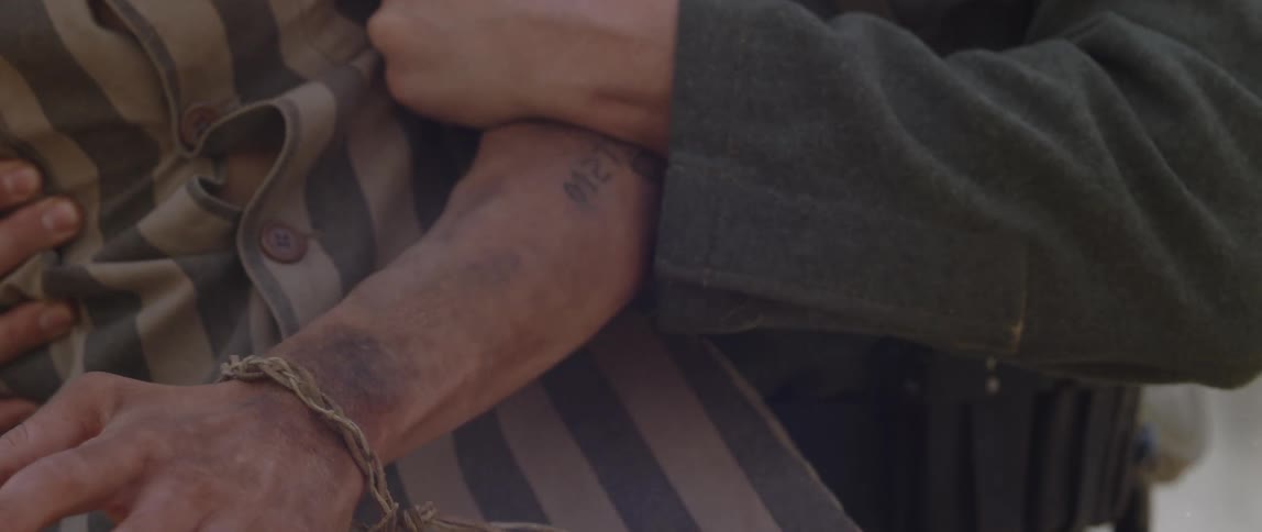 A soldier struggling to hold back a prisoner in a striped jumpsuit