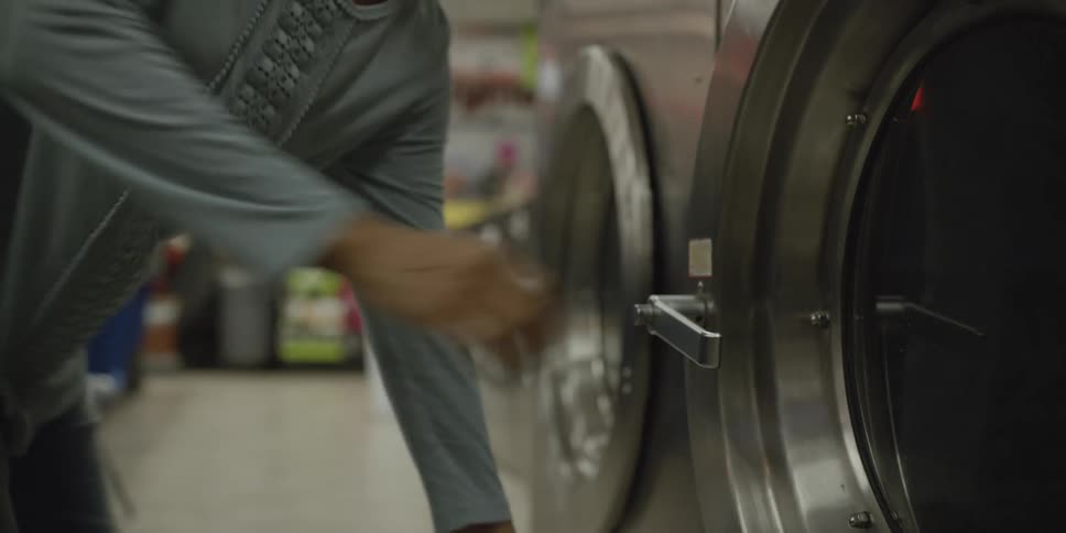 A woman is doing laundry at a laundromat in the middle of the day time