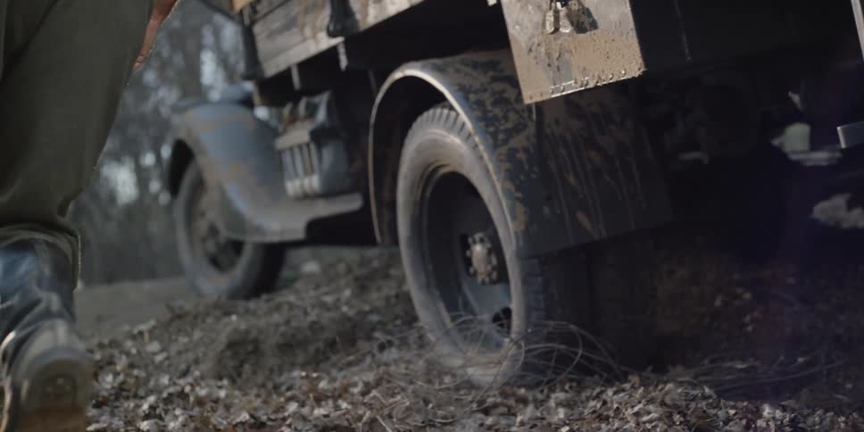 A pair of armed soldiers climb out of the rear of a truck and run to the front of the vehicle