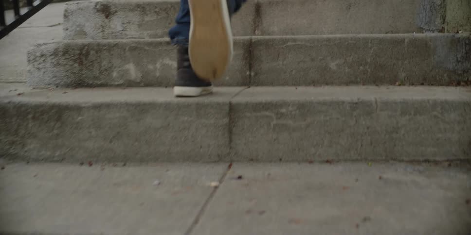 The sneakered feet and jean clad legs of a child running up cement steps