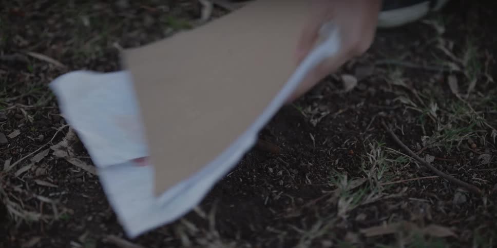 A boy picks his notebook off the ground outside
