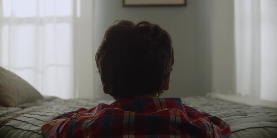 Boy kneels with his head on bed cryingbefore raising his head