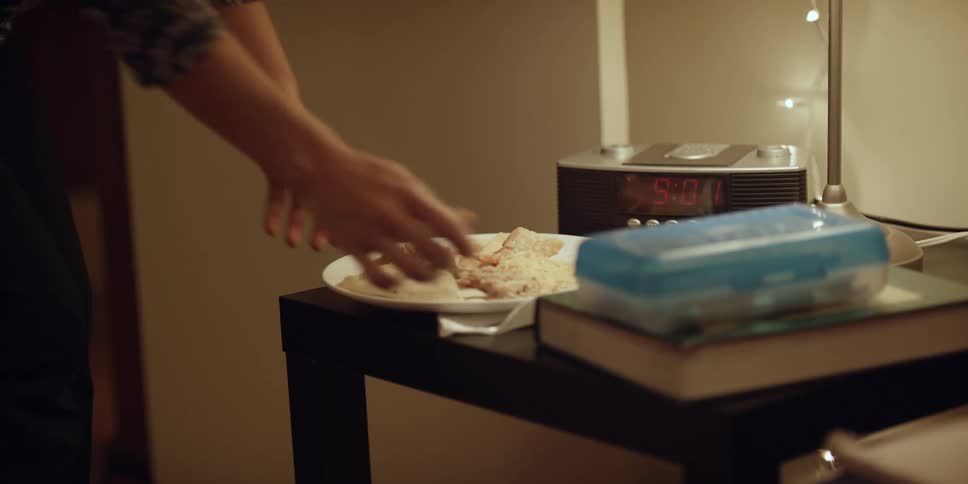 Woman puts a plate with food on nightstand in bedroom