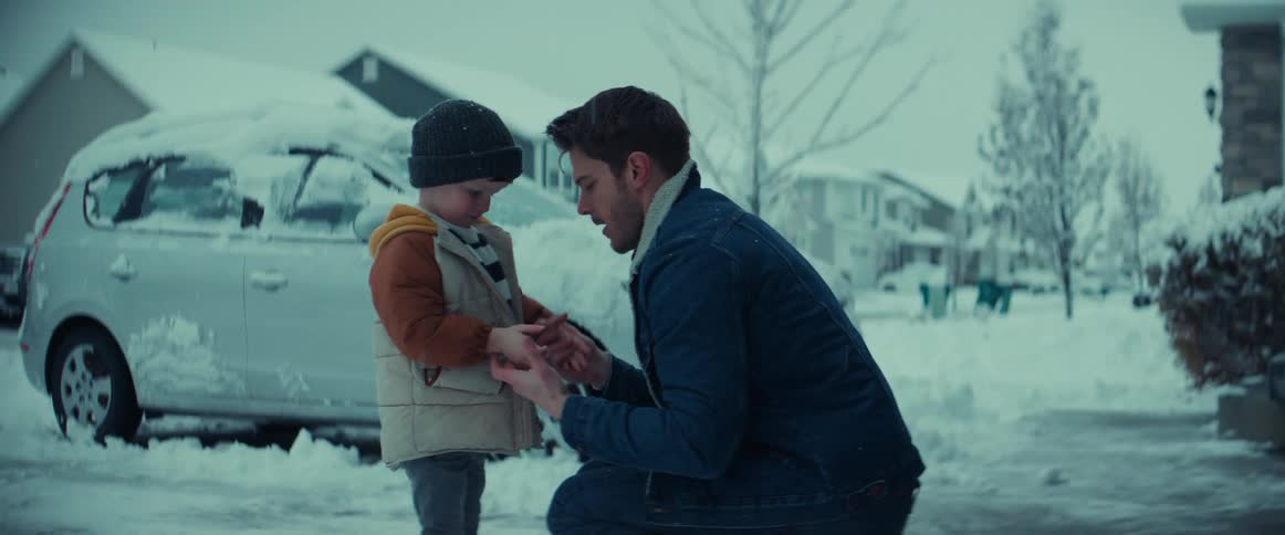 Father warms sons hands in snow