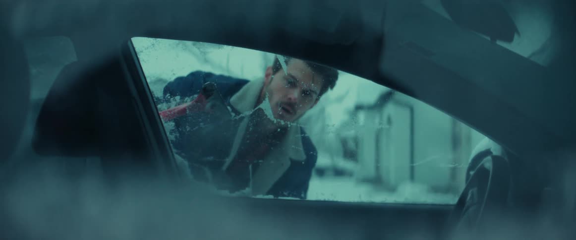 Man removes snow and ice from car sitting outside in winter