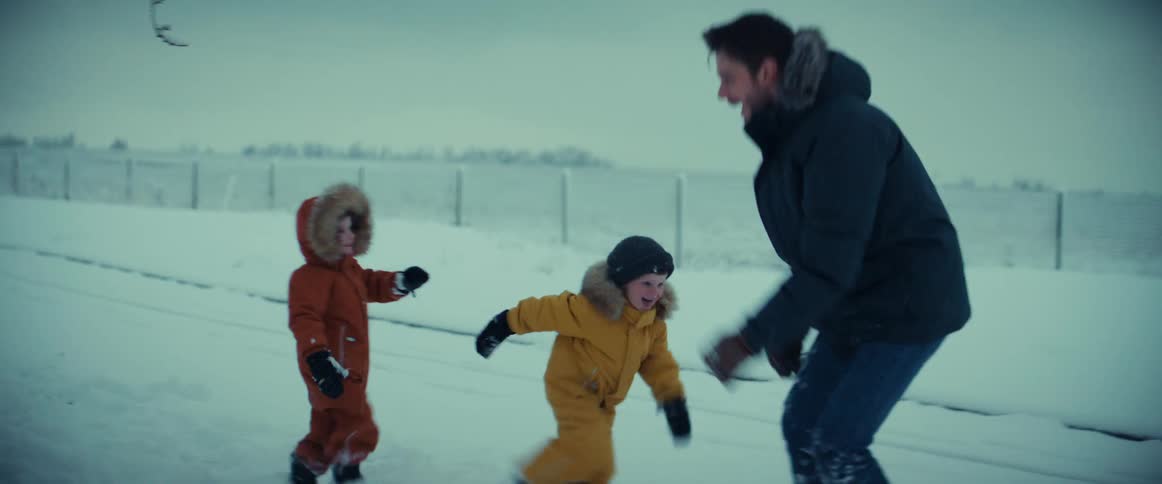Happy family playfully chasing each other on a field covered in snow at winter