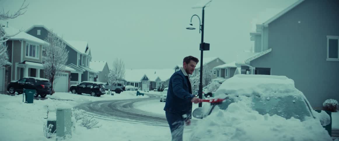 A man uses a snow brush and ice scraper