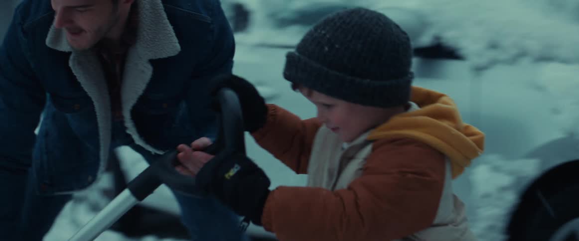 Man shows son how to push snow shovel