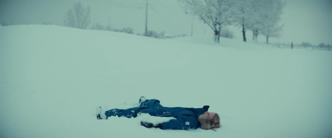 A young girl in a snow suit making a snow angel in winter