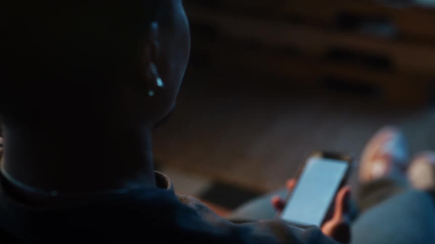 A person is sitting down and looking at their cellphone