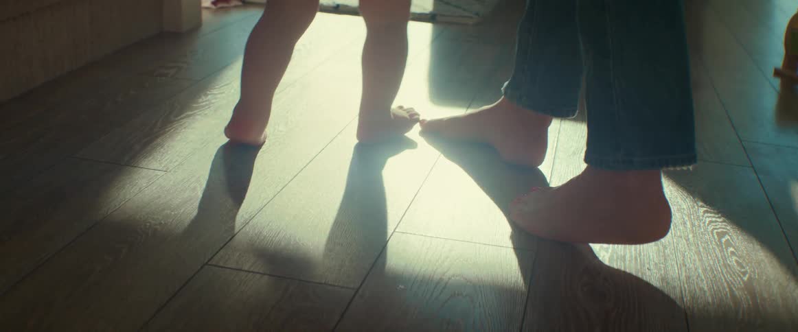 A mother helping her baby to walk on a wood floor