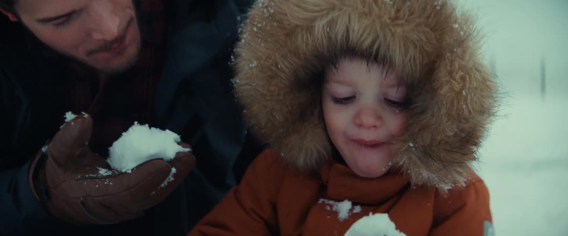 A man and a young boy eat snow outdoors on a winter day
