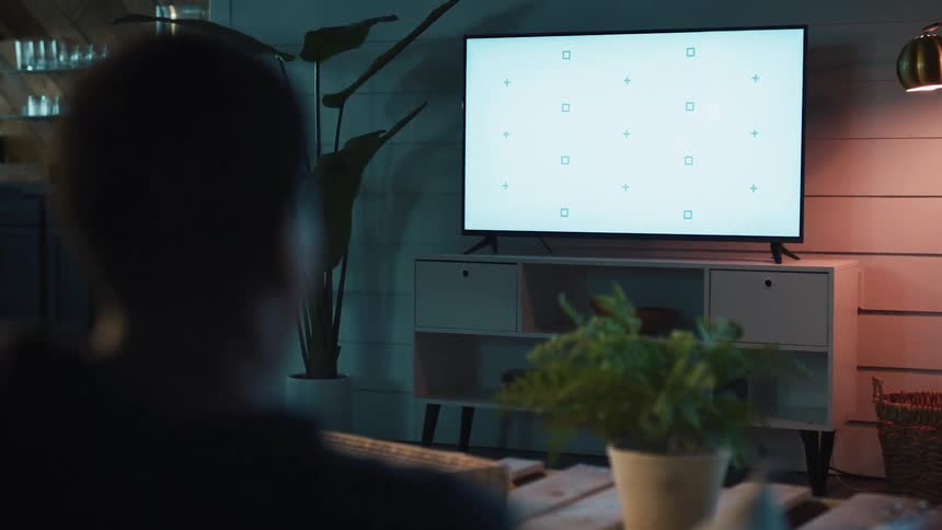 A man using a smartphone while watching television in a living room