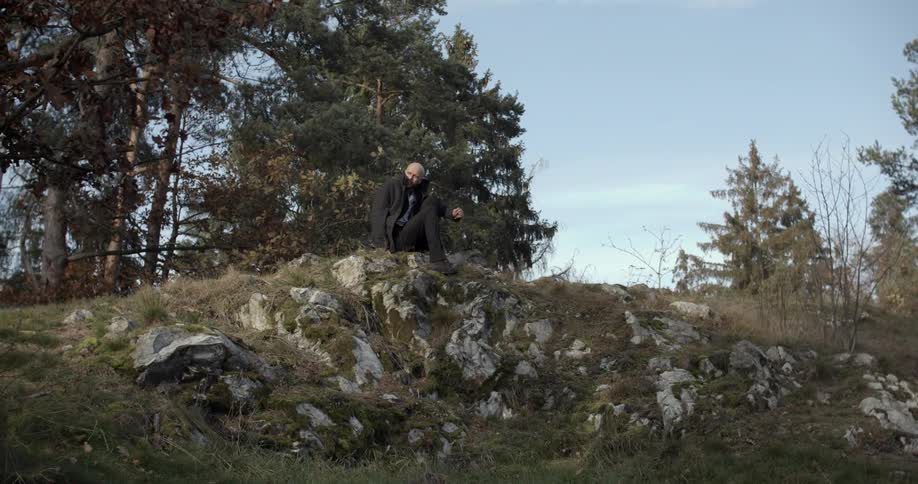 A man sits down on some rocks on a hill