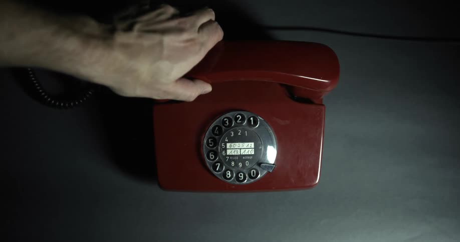 A man lifting the receiver from a rotary phone