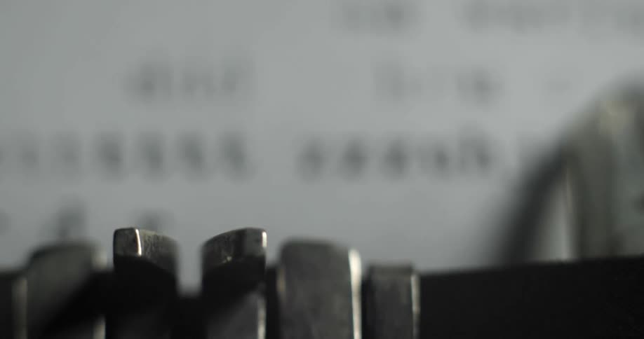 Keys on a typewriter strike ink tape and type on a page