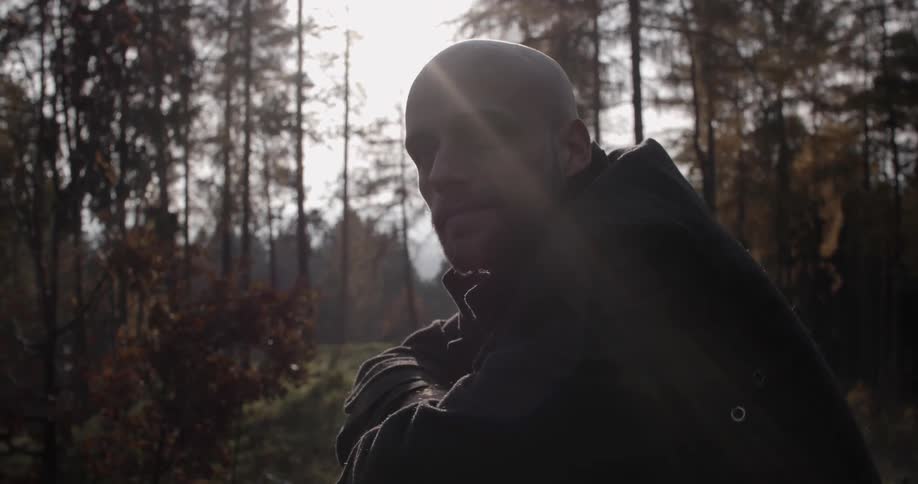 A bald man sits in a forest