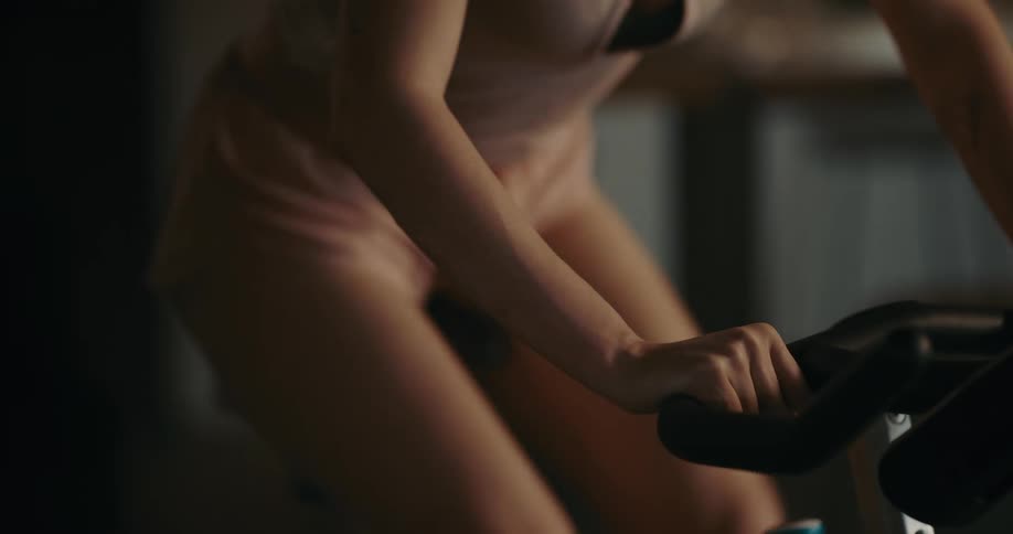 A woman sets smartphone down before working out on her exercise bike at home