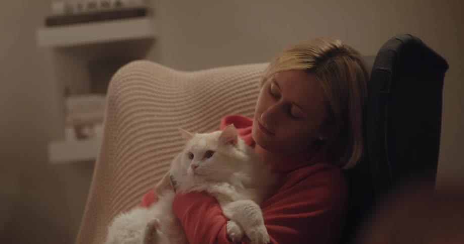A young woman is being affection with her cat inside of her home