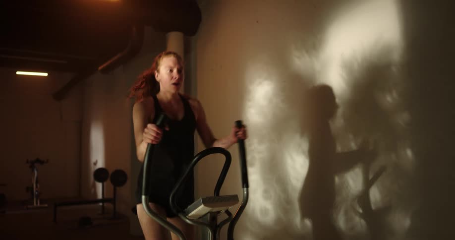 A woman is working out on an exercise machine as her arms and legs are moving vigorously