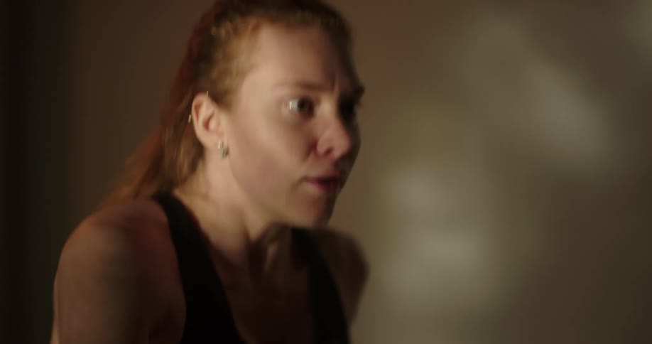 Redheaded woman exercises rapidly before stopping to drink water