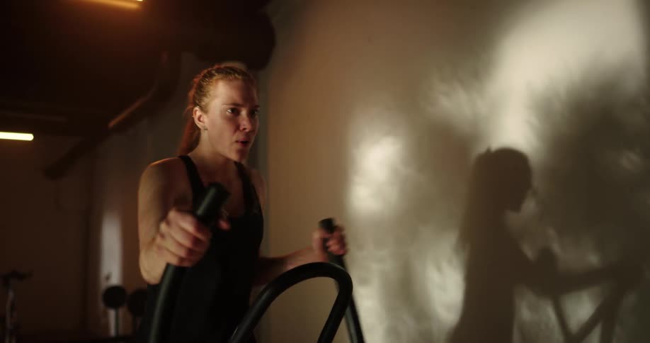 A woman is working out on an exercise machine as her arms and legs are moving vigorously