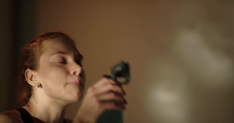 A woman drinking from a water bottle while working out on an elliptical machine