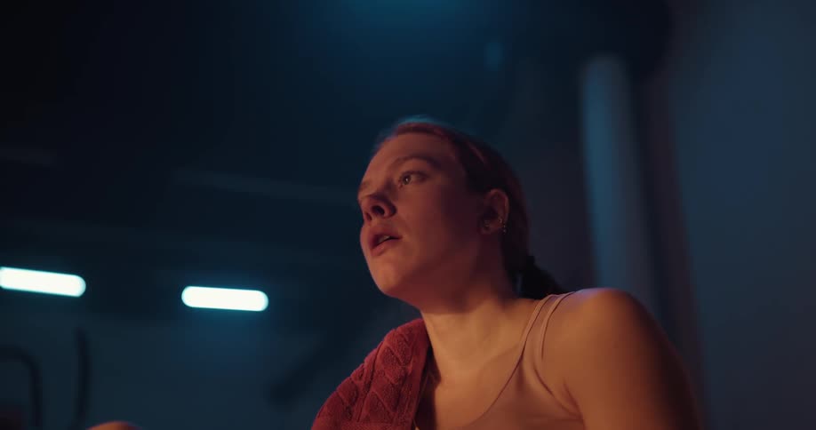 A young woman is at the gym and drinking some water