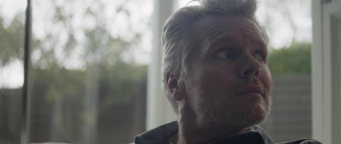A man is sitting indoors next to a window during spring